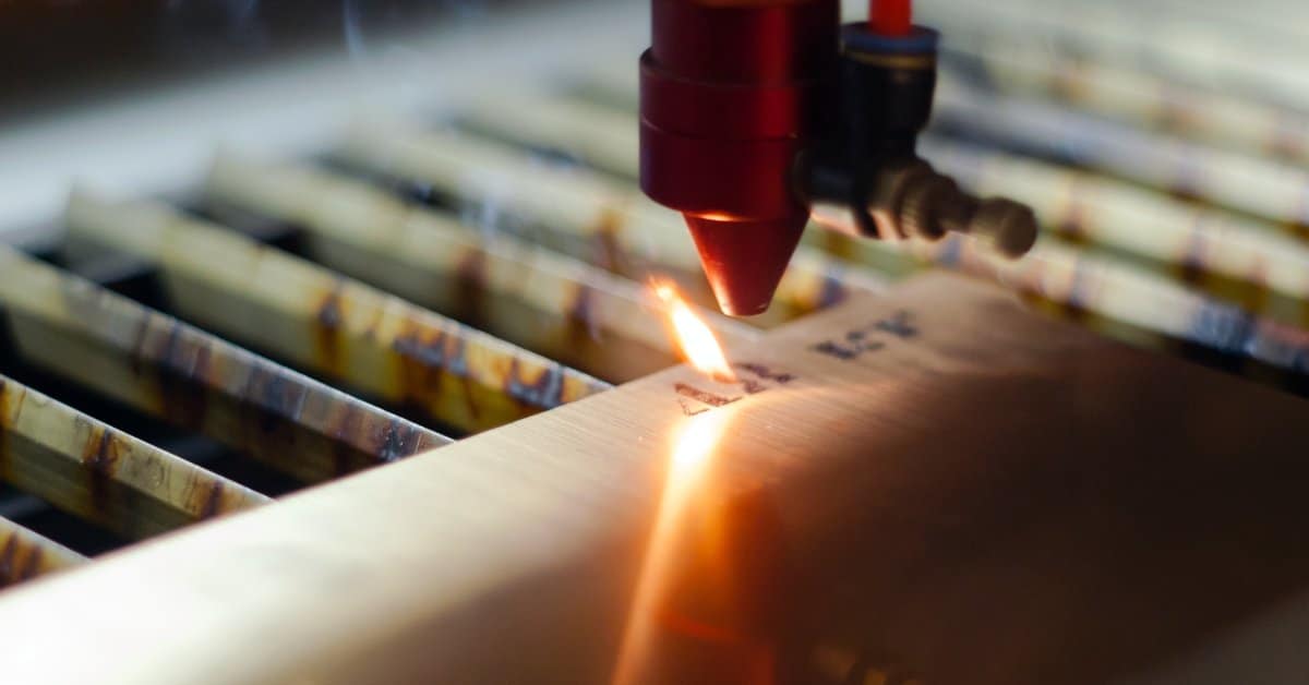 A laser marking machine burns a number mark into material over steel grates with a small flame from the mark.