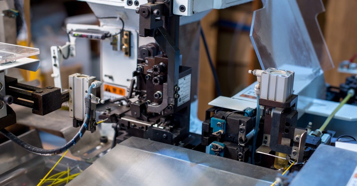 A full view of a modern automatic wire crimping machine at a workshop with various wires in clamps and holdings.