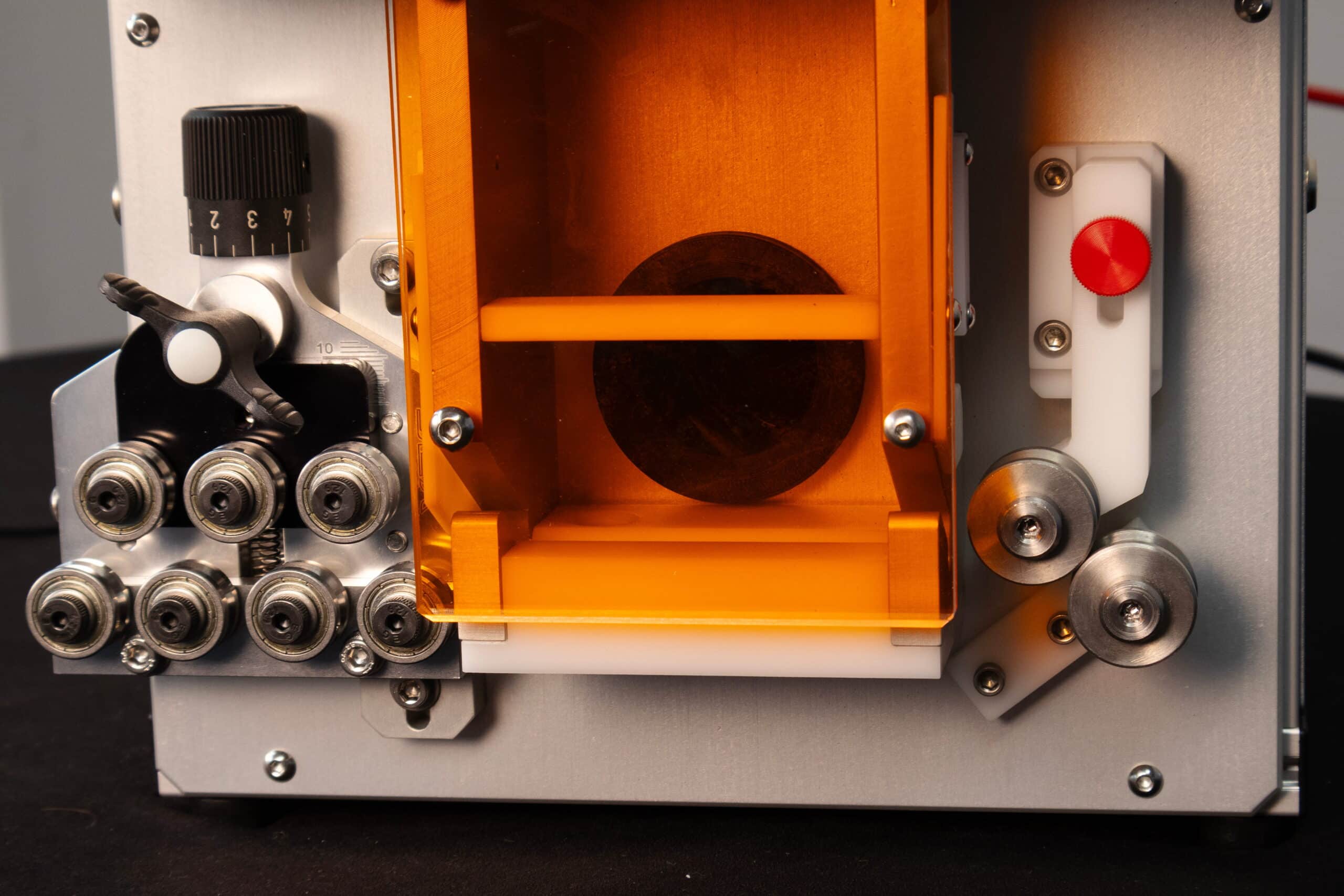 A close-up of the orange tube entrance door of the Tri-Star Technologies Econolase laser wire marking machine.