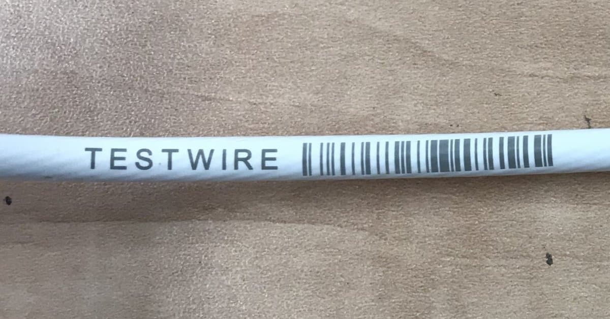 Close-up of a cable marked with custom text and a barcode, demonstrating durable wire identification for tracking and installation purposes.